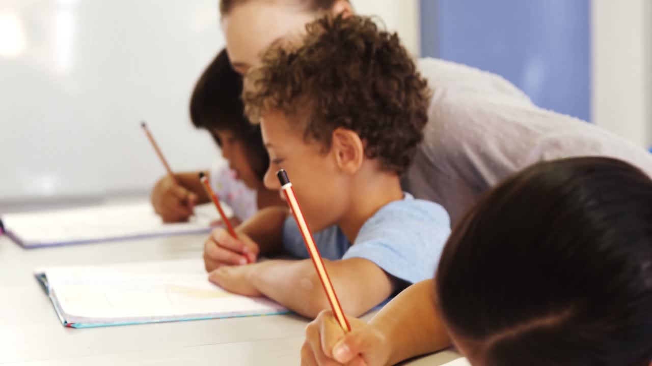 niños escribiendo y un maestro ayudando a uno