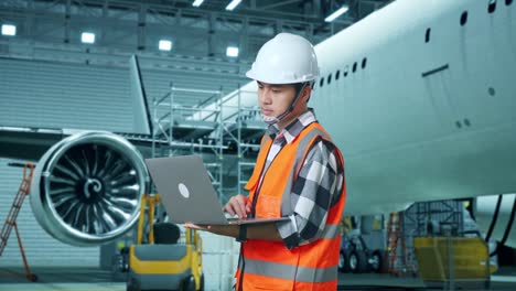 mecánico de aviones trabajando en una computadora portátil en un hangar