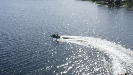 aerial view of young men driving a jet ski with a ringo ride in river water