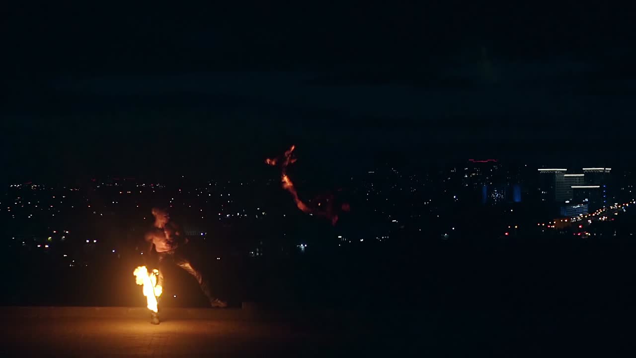 젊은 금발 남성이 큰 불의 흐름을  ⁇ 아내며 느린 움직임을 찍습니다.