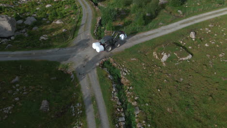 tractor moviendo fardos de ensilaje al granero para su almacenamiento.
