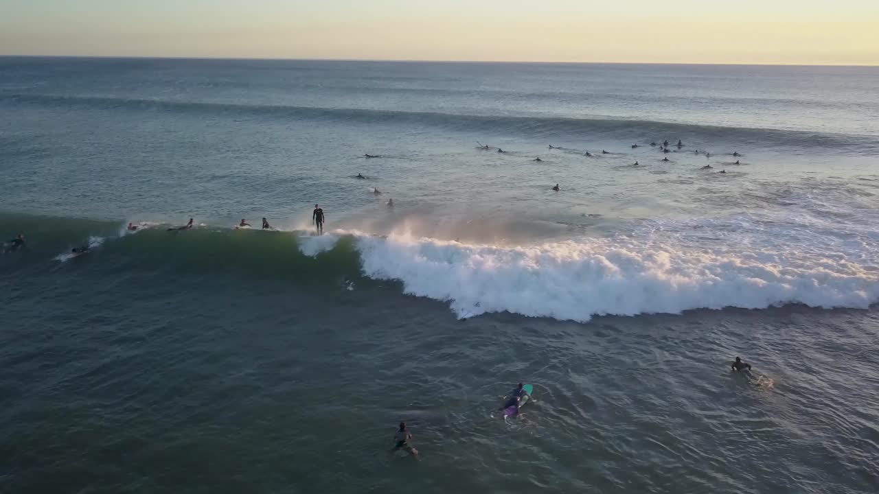 Mentre il sole tramonta, un surfista di longboard cavalca un'onda, catturando la magia di un'incredibile sessione serale sulle onde in Europa