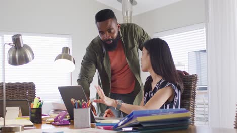 Diverse-male-and-female-friends-using-laptop-and-talking,-working-at-home,-in-slow-motion