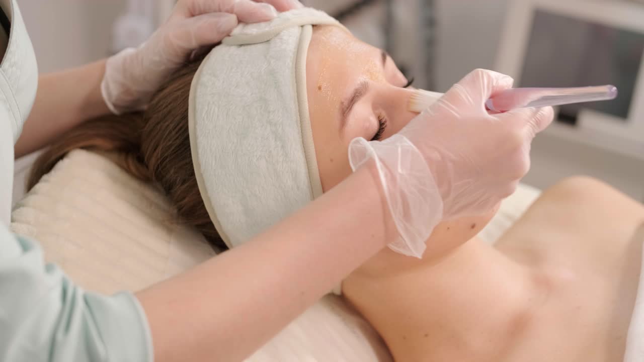 Profesjonelle ansiktspleieprosedyrer på en moderne kosmetologiklinikk. Hudpleier utfører ansiktsbehandlinger – rensing, maske, peeling, karboksyterapi.