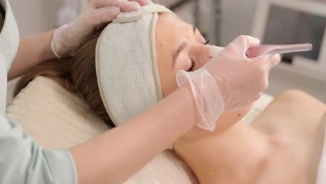 professional face care procedures in the modern cosmetology clinic. beautician is doing face treatment procedures - purification, mask, peeling, carboxytherapy