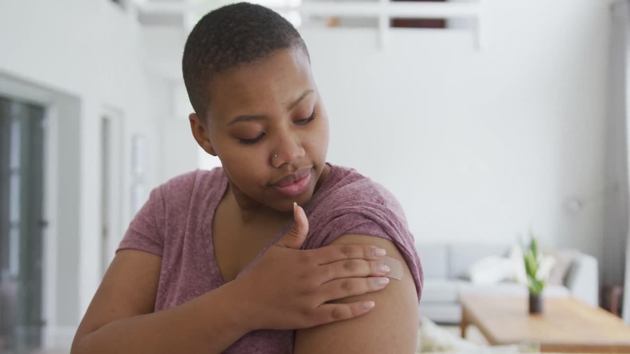 Portrait of smiling african american plus size woman with bandage on her arm after vaccination
