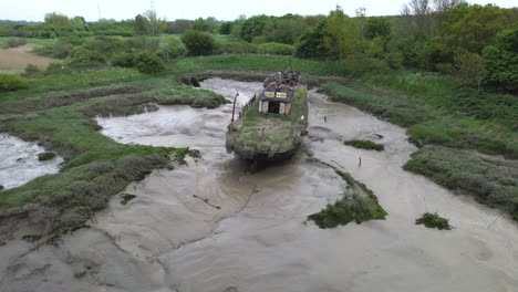 abandoned overgrown boat wreck stranded in wat tyler muddy riverbed aerial orbit view