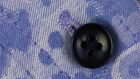 black plastic sew button attach on blue woven-patterned fabric