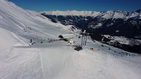 Bergsesselliftstation-Mit-Leuten,-Die-Aussteigen-Und-Die-Pisten-Hinunterfahren