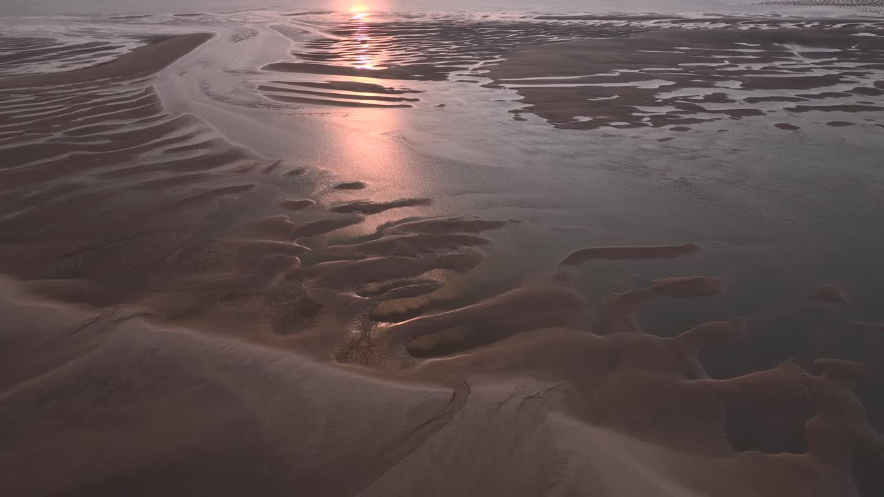 Sunset on sand patterns and pool reflections at low tide on tidal sand banks. Reverse flight over.
