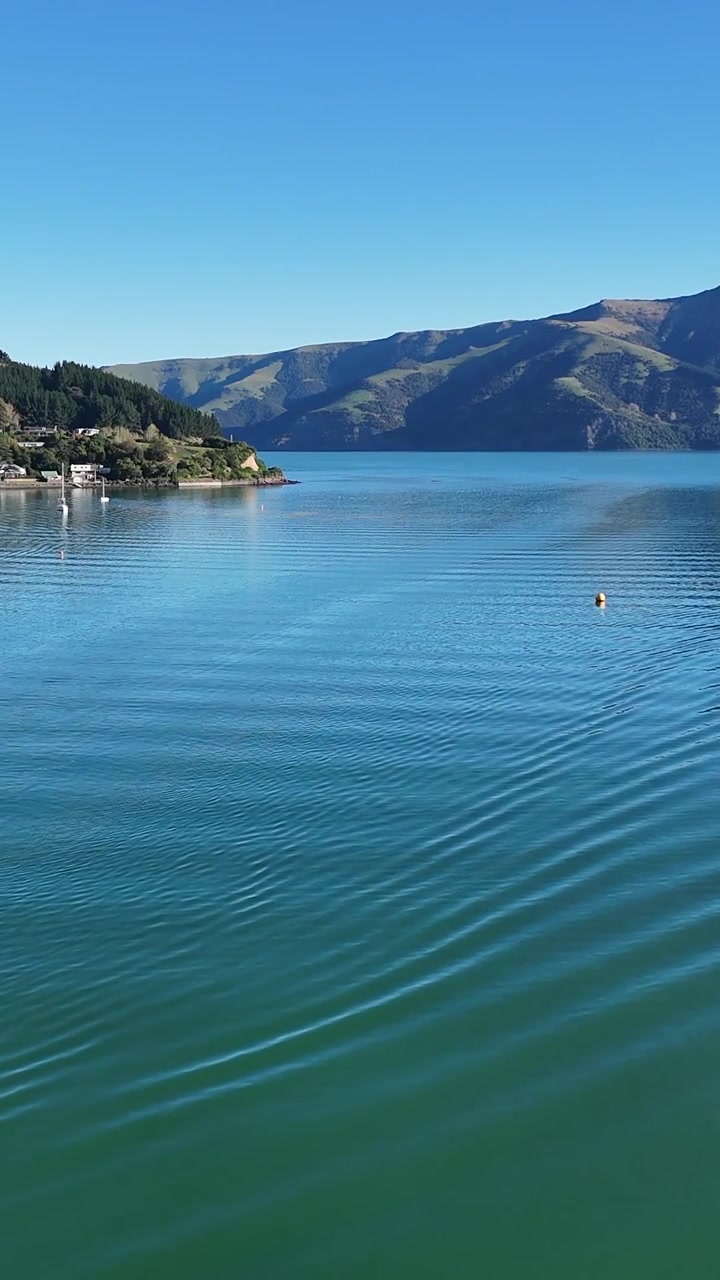 Una serena inquadratura verticale di delicate increspature dell'acqua che si muovono verso una costa montuosa lontana.