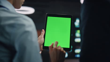 businesspeople hands holding greenscreen tablet computer at datacenter closeup.