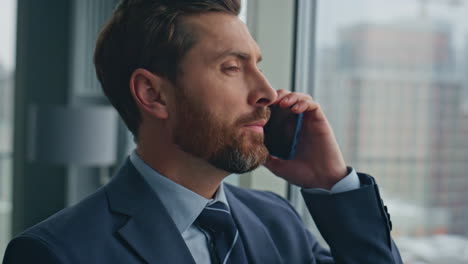 closeup serious man calling smartphone at panoramic window. executive talking