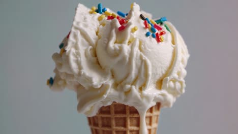 close-up video of a melting ice cream cone with colorful sprinkles, shot from a low angle