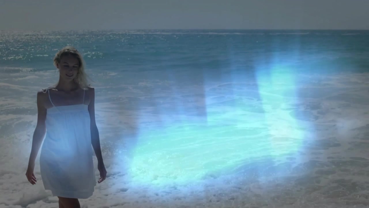 Demo tecnologica che mostra una donna che cammina lungo la costa mentre una luce blu orizzontale si sposta, cambia e si ritira