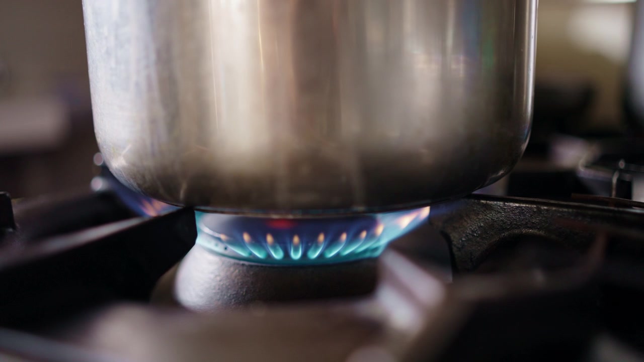 Primo piano di piano cottura a gas, fiamma del gas, pentola sopra
