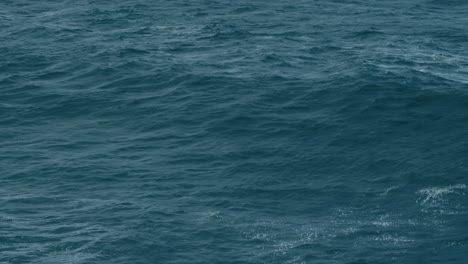 cinematic aerial shot of dark blue ocean surface, moody sea waves, deep ocean