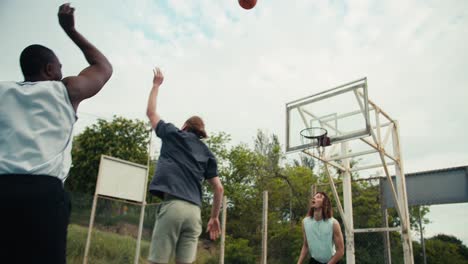 un grupo de amigos están jugando al baloncesto. una persona negra dribble, un hombre trata de marcar un gol y sus amigos lo ayudan