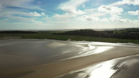 Luftaufnahme-Eines-Strandes-Bei-Ebbe-Mit-Der-Sonne,-Die-Auf-Dem-Nassen-Sand-Schimmert,-Heller-Sonniger-Tag