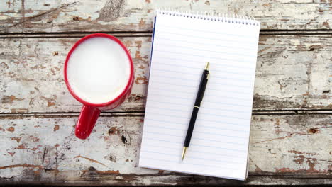 coffee cup, notepad, pen on wooden plank