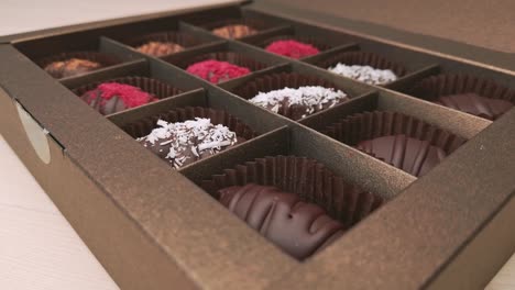 chocolate candies in crafting gift box extreme close up. 4k closeup footage of camera slowly moving between assorted chocolates confectionery on the white background