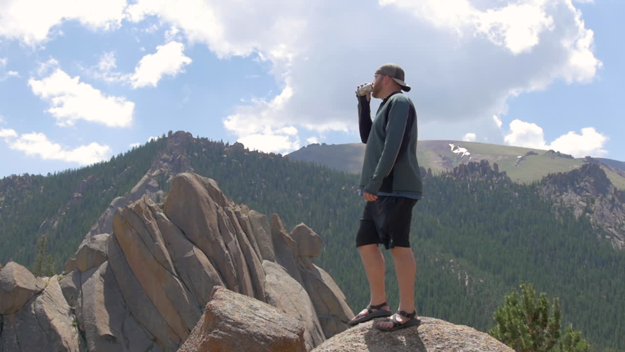 Epic Shot of a Man Drinking Soda on top of a Mountain in Colorado, Slow Motion