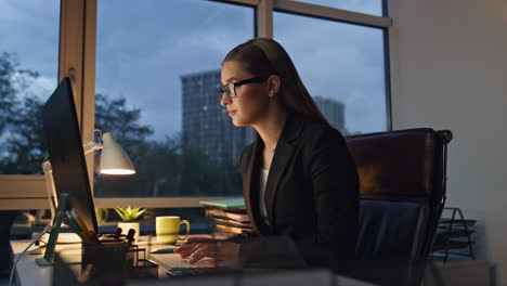 beautiful manager typing computer in dark office. pensive woman ponder business