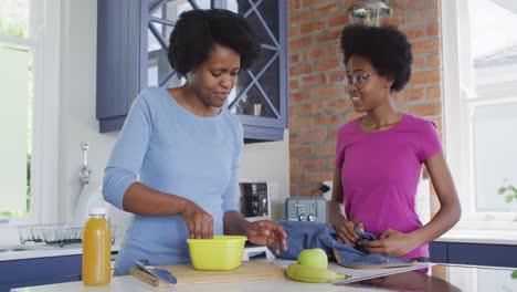 Happy-african-american-mother-and-daughter-packing-lunch-for-school