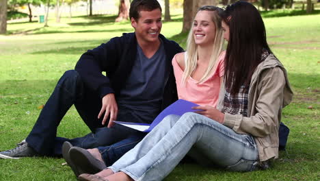 tres amigos riendo mientras leen un libro juntos en un parque