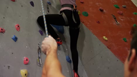 Coach-assisting-a-woman-in-climbing-the-artificial-wall-4k