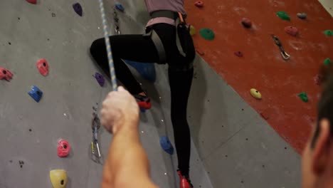 coach assisting a woman in climbing the artificial wall 4k