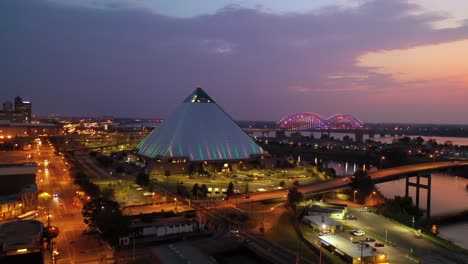 Hermosa-Noche-Toma-Aérea-De-La-Pirámide-De-Memphis,-El-Puente-Hernando-De-Soto-Y-El-Paisaje-Urbano-Al-Atardecer-1