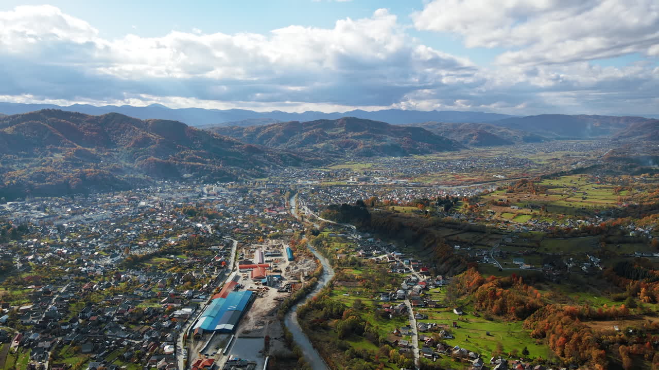 Aerial drone view of Viseu de Sus, Romania. A lot of residential buildings, river, hills covered with yellowing forest