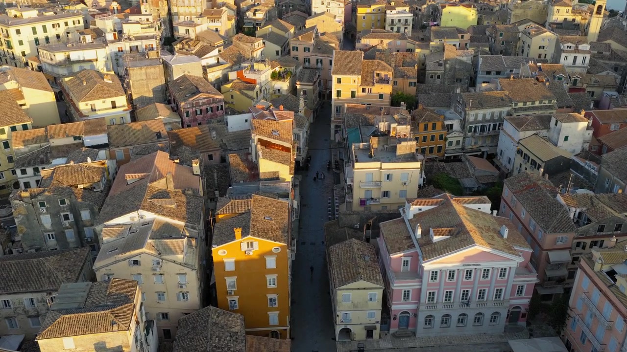 Primo piano aereo di edifici tradizionali nel centro storico di Corfù, tra vicoli stretti, sotto la luce dorata del sole, vicino alla piazza della chiesa di San Spiridione