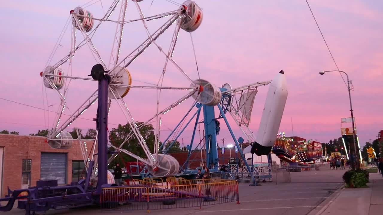 Zooming in to carnival rides in a small town at dusk.