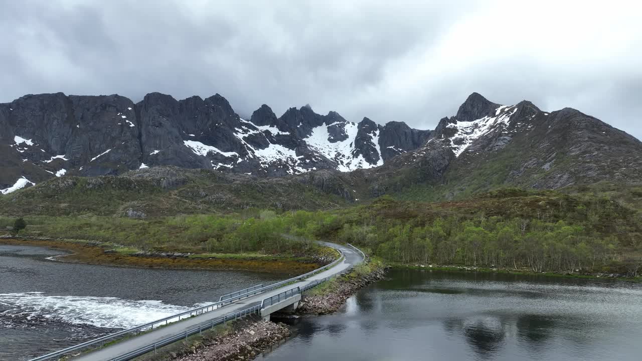 Forward aerial over road near Svolvaer tilting up towards Glomtind mountains and trolldalen valley