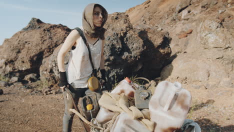 post apocalyptic woman pushing cart in rocky desert