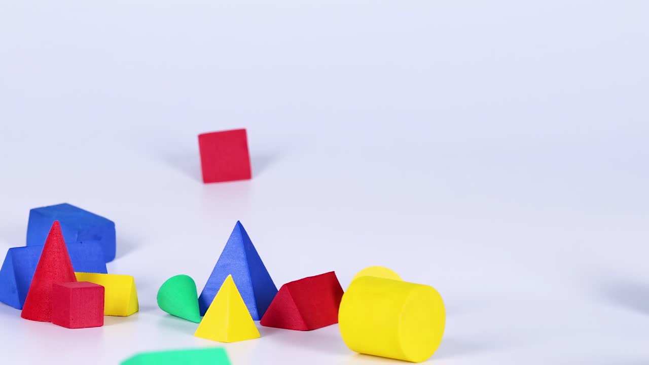 Colorful geometric shapes bounce and interact dynamically against a plain backdrop, showcasing playful movement and balance.