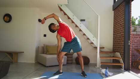 hombre afroamericano en forma haciendo ejercicio en casa y estirándose en casa