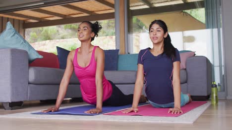 Video-of-happy-diverse-female-friends-practicing-yoga-together-at-home