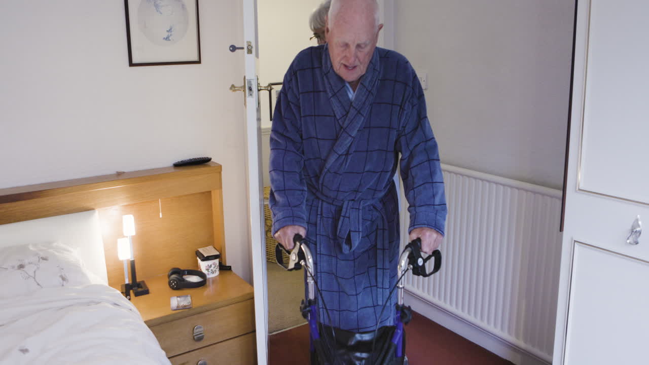 Elderly man using a walker with assistance at home