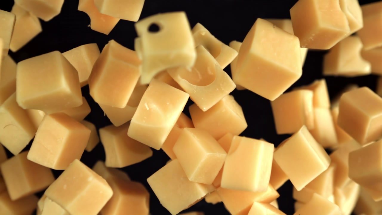 Cubetti di formaggio che cadono al rallentatore su sfondo nero