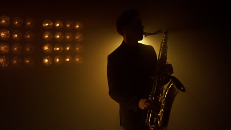 Silhouette-man-saxophonist-playing-instrument-on-stage.-Guy-playing-sax-in-club.