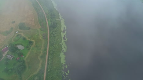 vista a vista de pájaro entre las nubes por encima de un paisaje verde en el borde de un lago