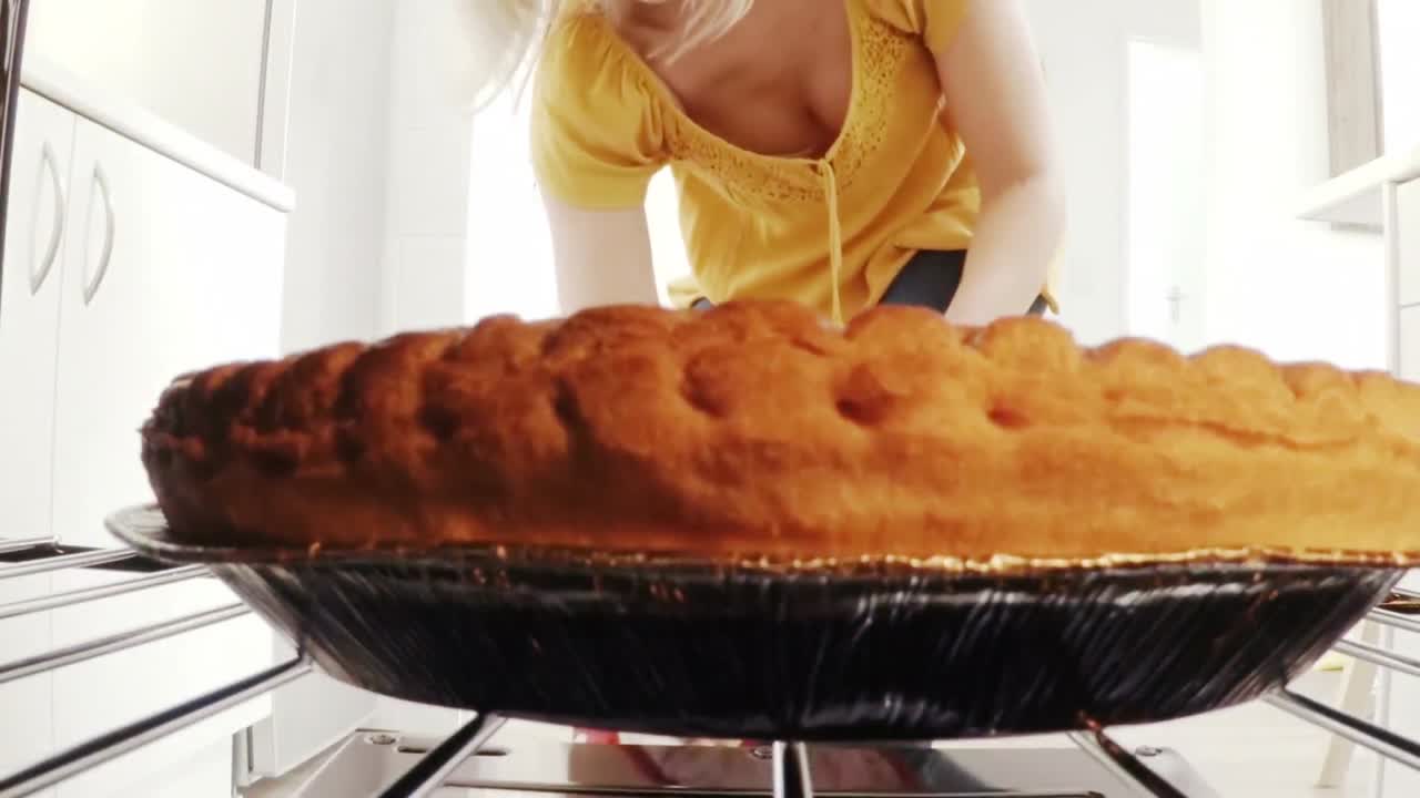 Žena vyndává pečicí plech se sladkým pečivem z trouby