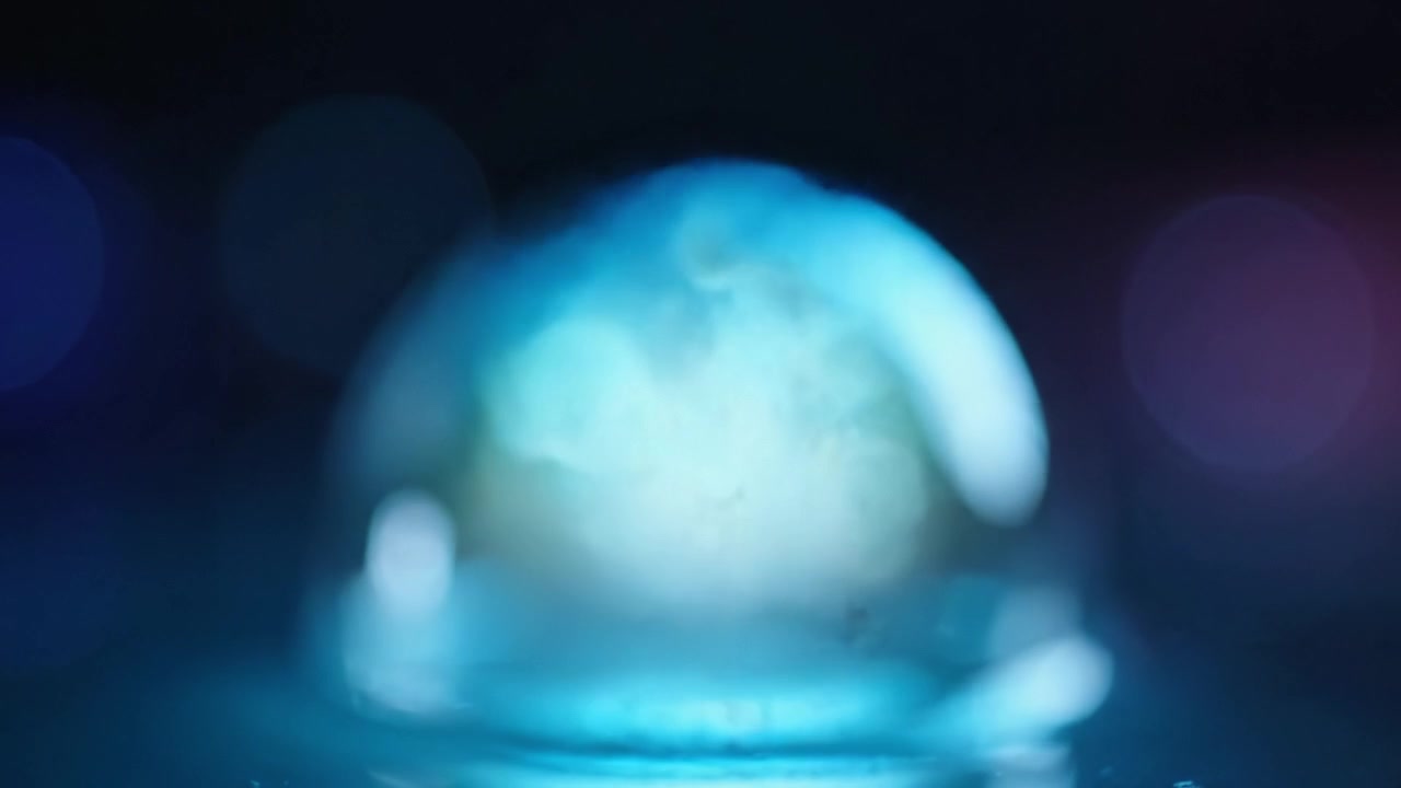 Uno spettacolo ipnotico di una cupola traslucida che riflette vivaci tonalità di blu, catturando la bellezza incantevole dell'interazione tra luce e acqua in un ambiente sereno.