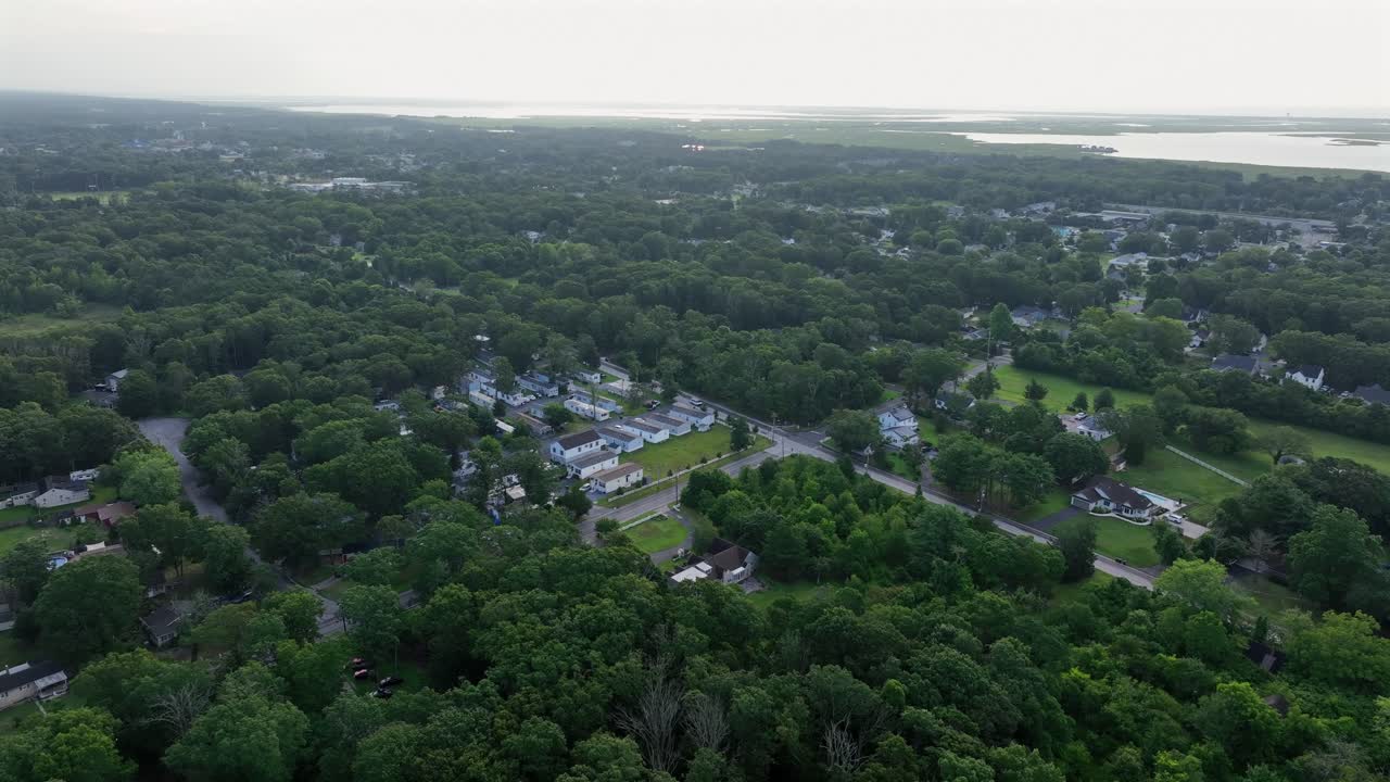Zona residenziale suburbana tra alberi verdi di Stone Harbor nel New Jersey. Alba al mattino dietro zone umide e campi paludosi. Ampia ripresa aerea