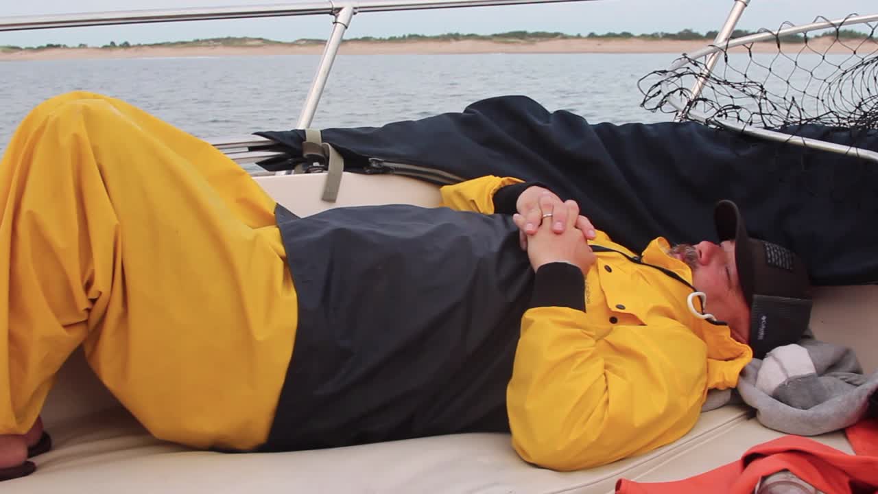 어부는 늦은 아침, 고정식 핸드헬드 동안 보트의 뱃머리에서 휴식을 취합니다.