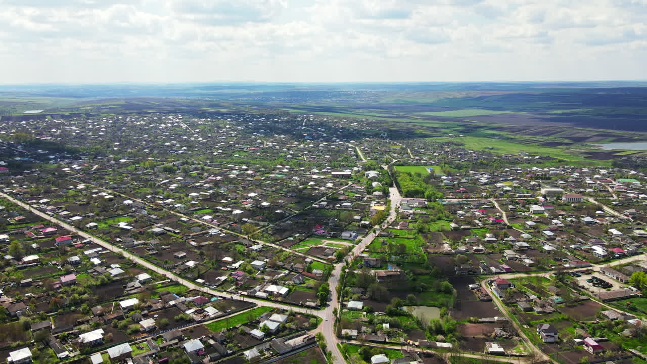 Aerial drone view of a village in spring in Moldova. Cloudy sky, greenery, hills and fields