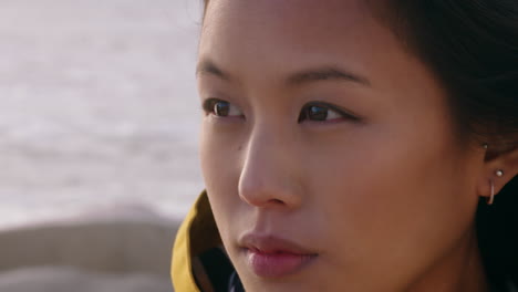 close up portrait beautiful asian woman enjoying freedom exploring wanderlust feeling relaxed on seaside contemplating spirituality at sunset with wind blowing hair